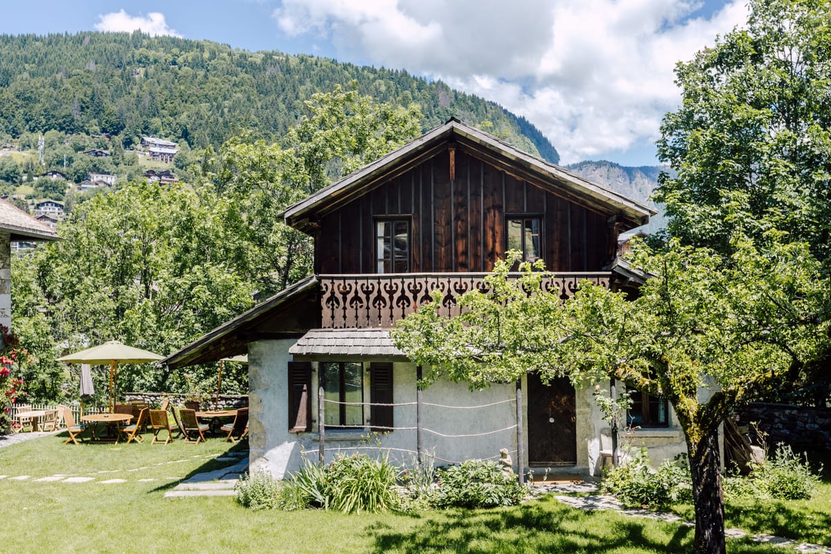 Wooden chalet outbuilding in the hotel garden, with forested mountains behind
