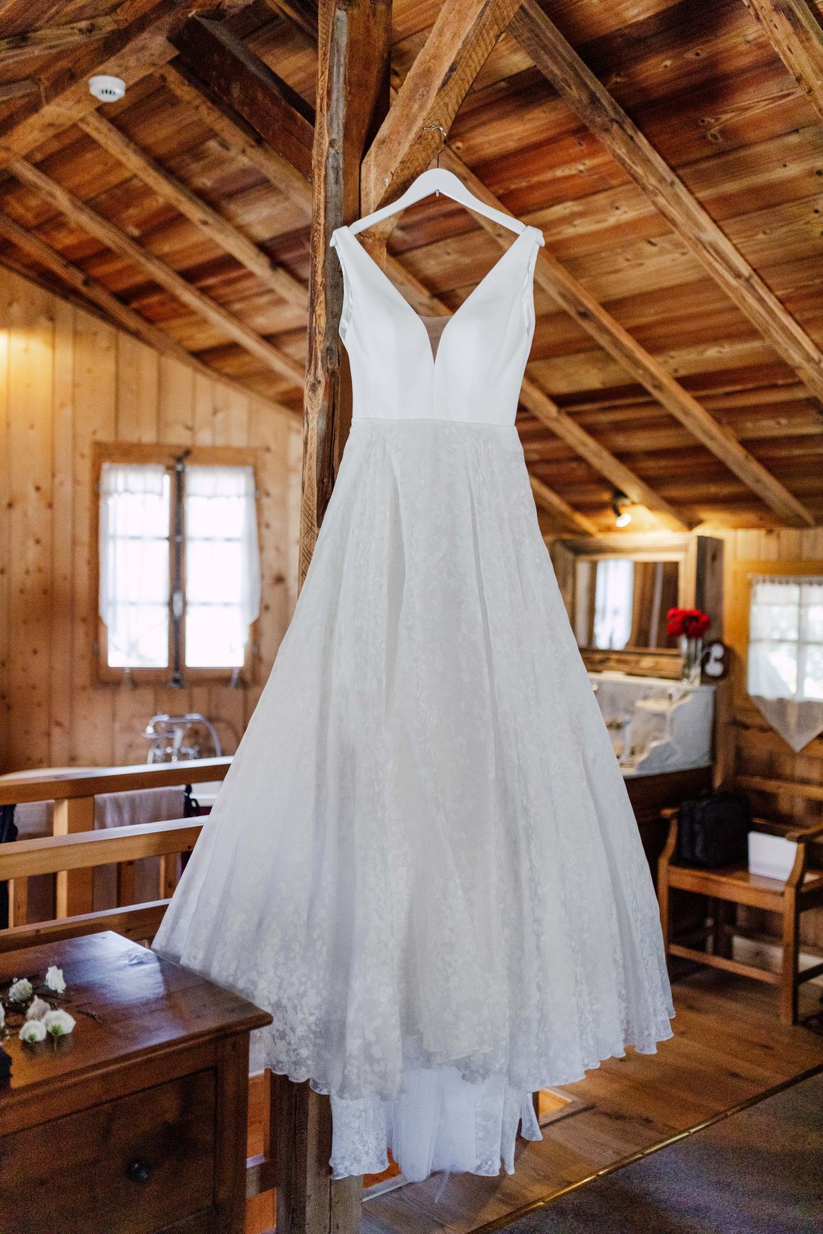 Wedding dress hanging from a beam in a wooden room