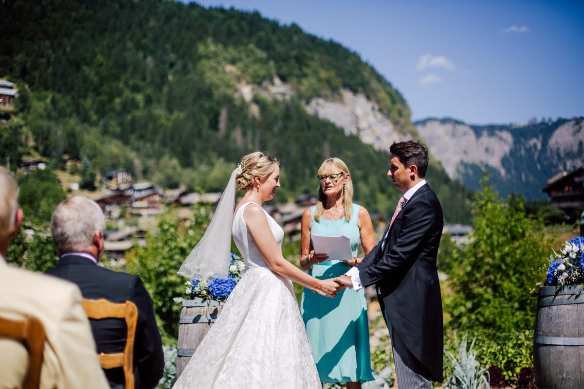 Bride and groom exchanging vows in the garden, with mountains behind