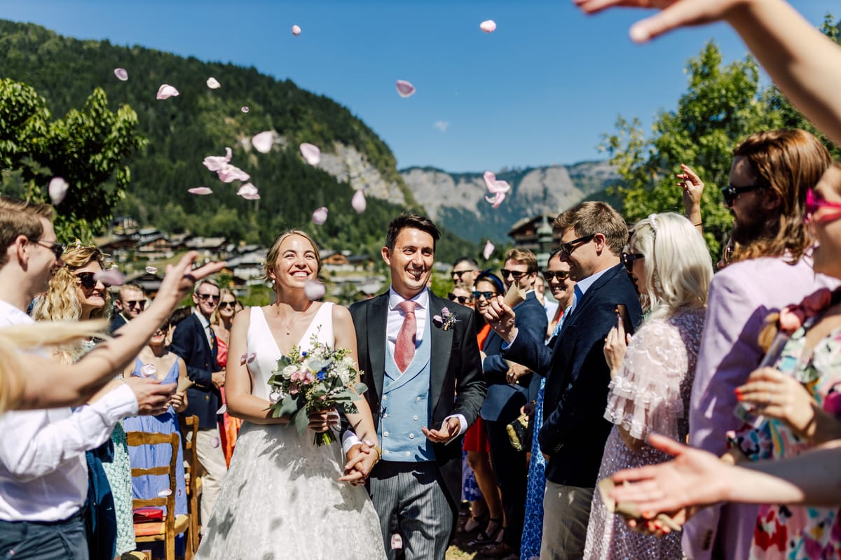 Guests throwing petals as the bride and groom walk back up the aisle