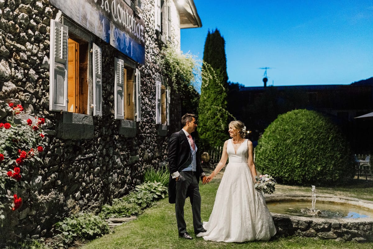 Bride and groom beside the fountain in front of the stone house