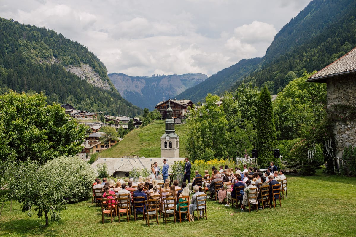 Guests seated in rows for a garden ceremony, with the valley and mountains behind