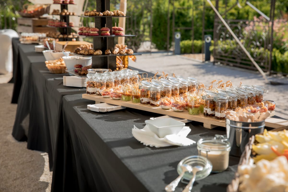 A catering table with a wooden board of desserts and canapes