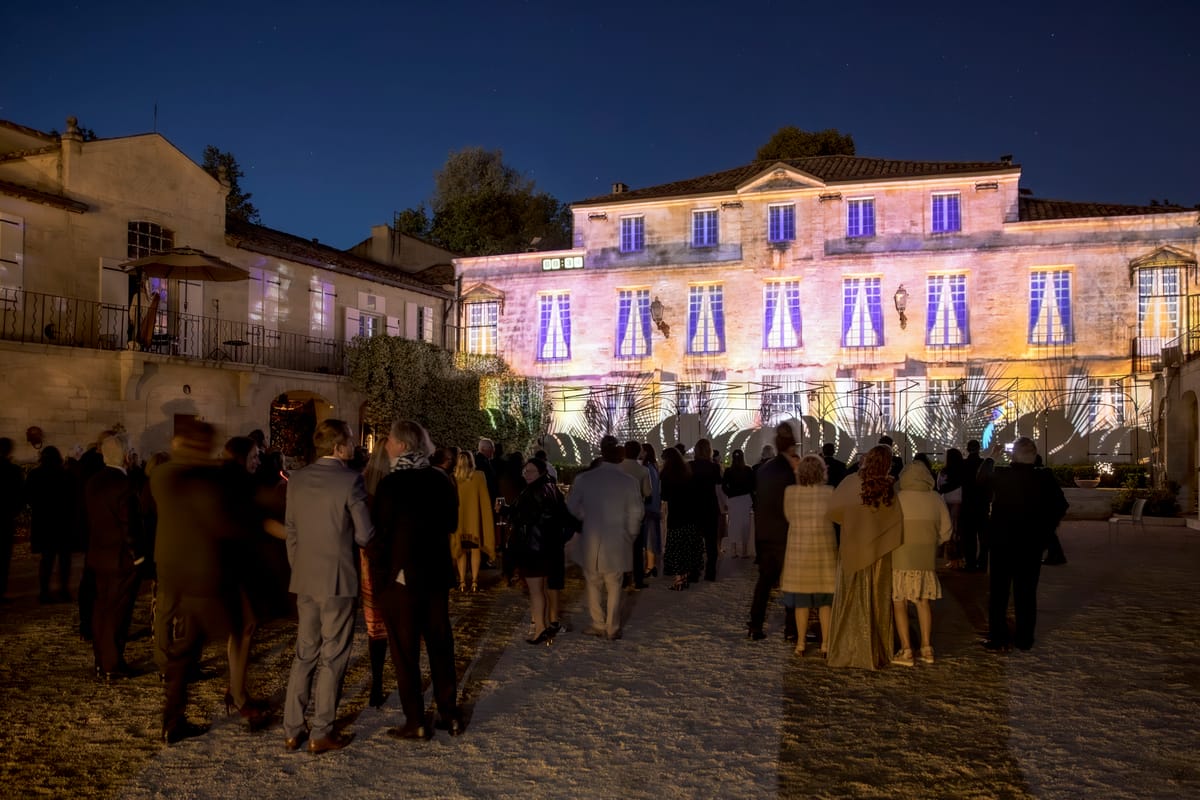 The chateau facade lit with an evening light display, guests gathered in the courtyard