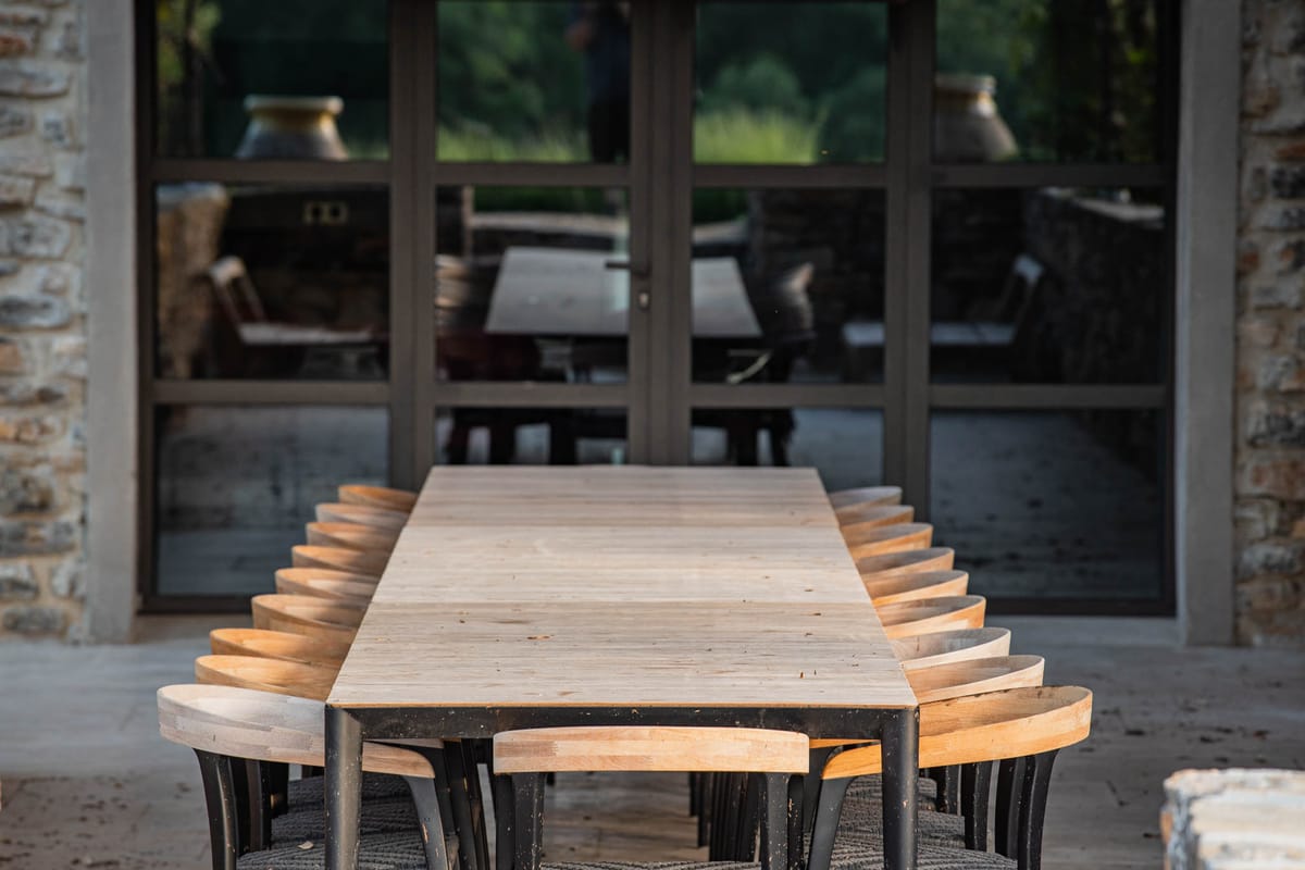 Long oak banquet table inside covered stone dining hall at Domaine de Blacailloux