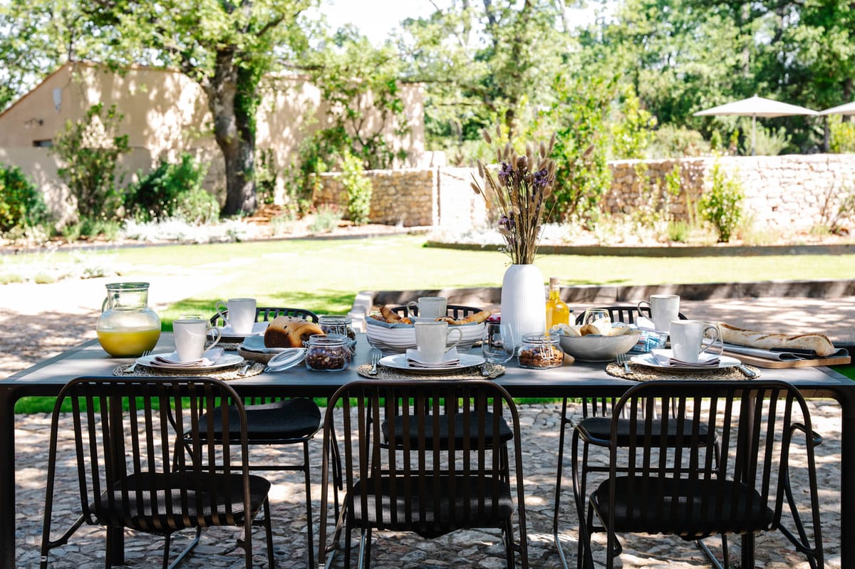 Outdoor garden breakfast table with juice, brioches and dried grasses at Domaine de Blacailloux