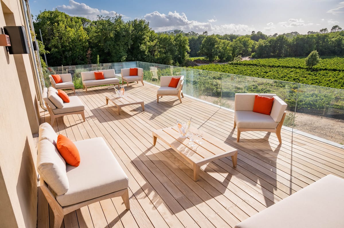 Rooftop terrace lounge with cream sofas and orange cushions overlooking vineyards at Domaine de Blacailloux