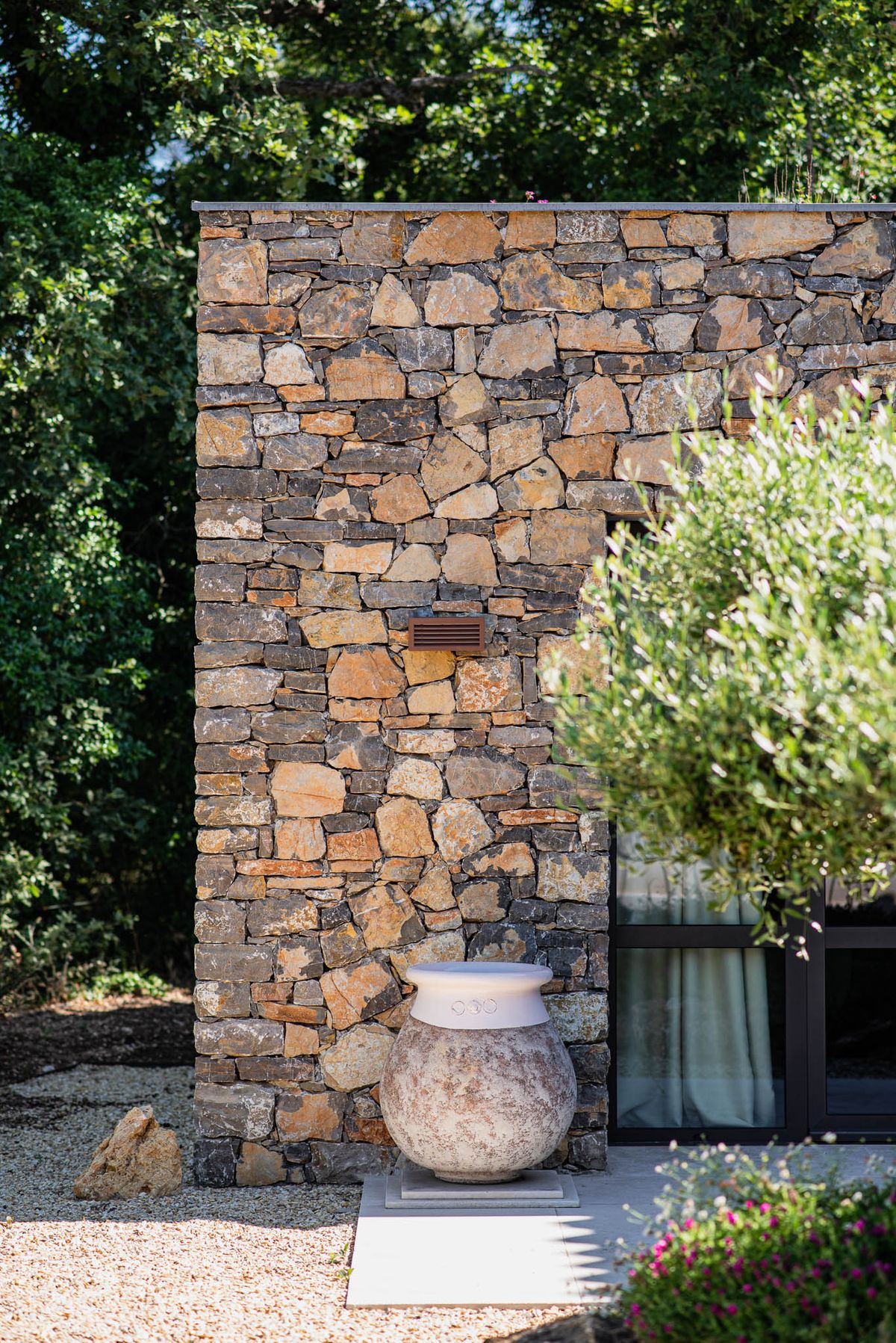 Close detail of local stone wall with terracotta urn and olive tree at Domaine de Blacailloux