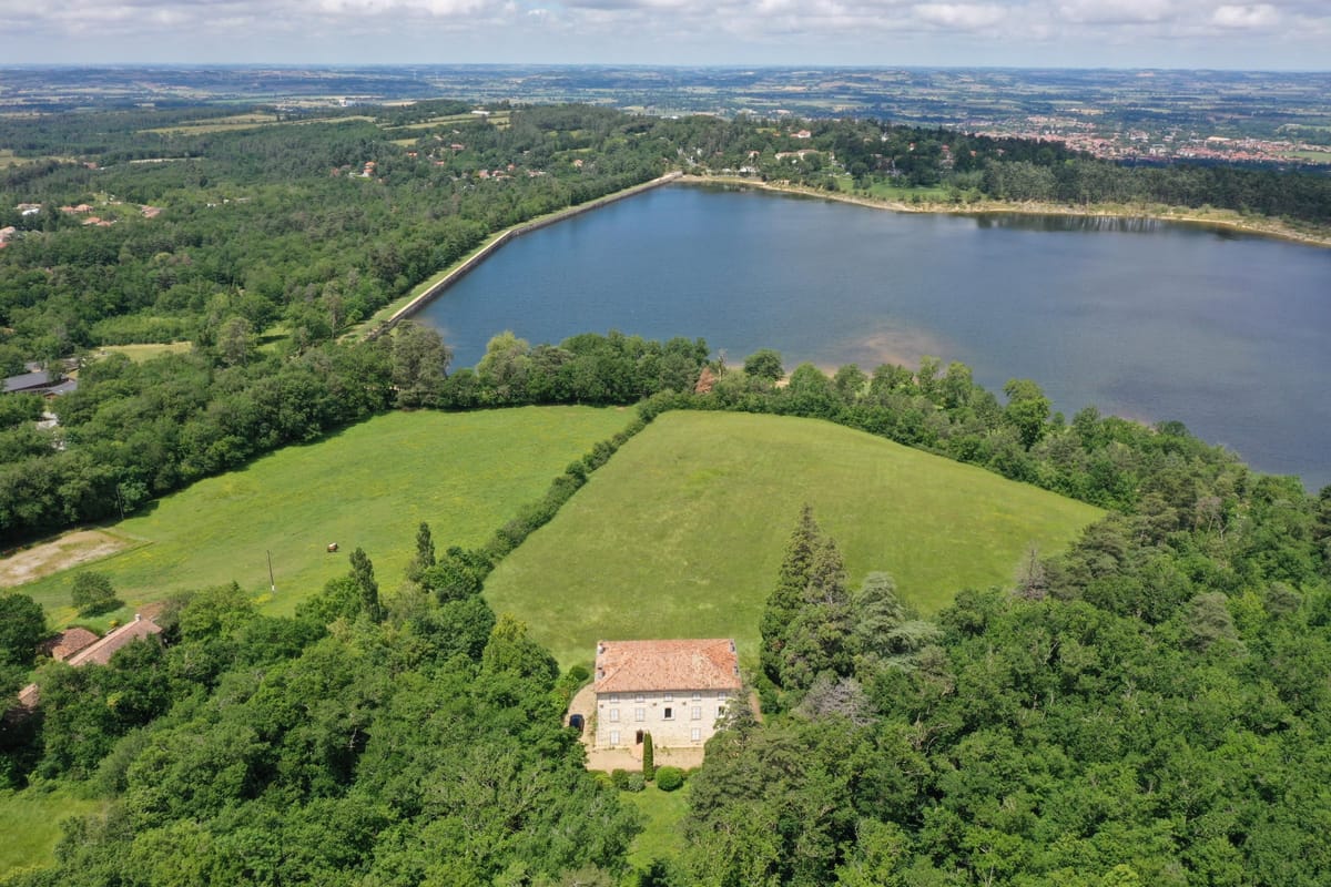 Aerial view over the lake and surrounding countryside, with the château set among the trees