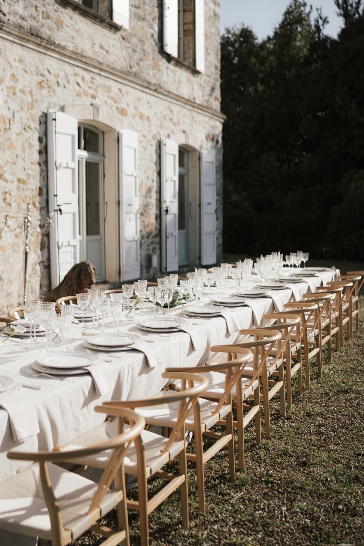 A long table laid for dinner beside the château's shuttered windows
