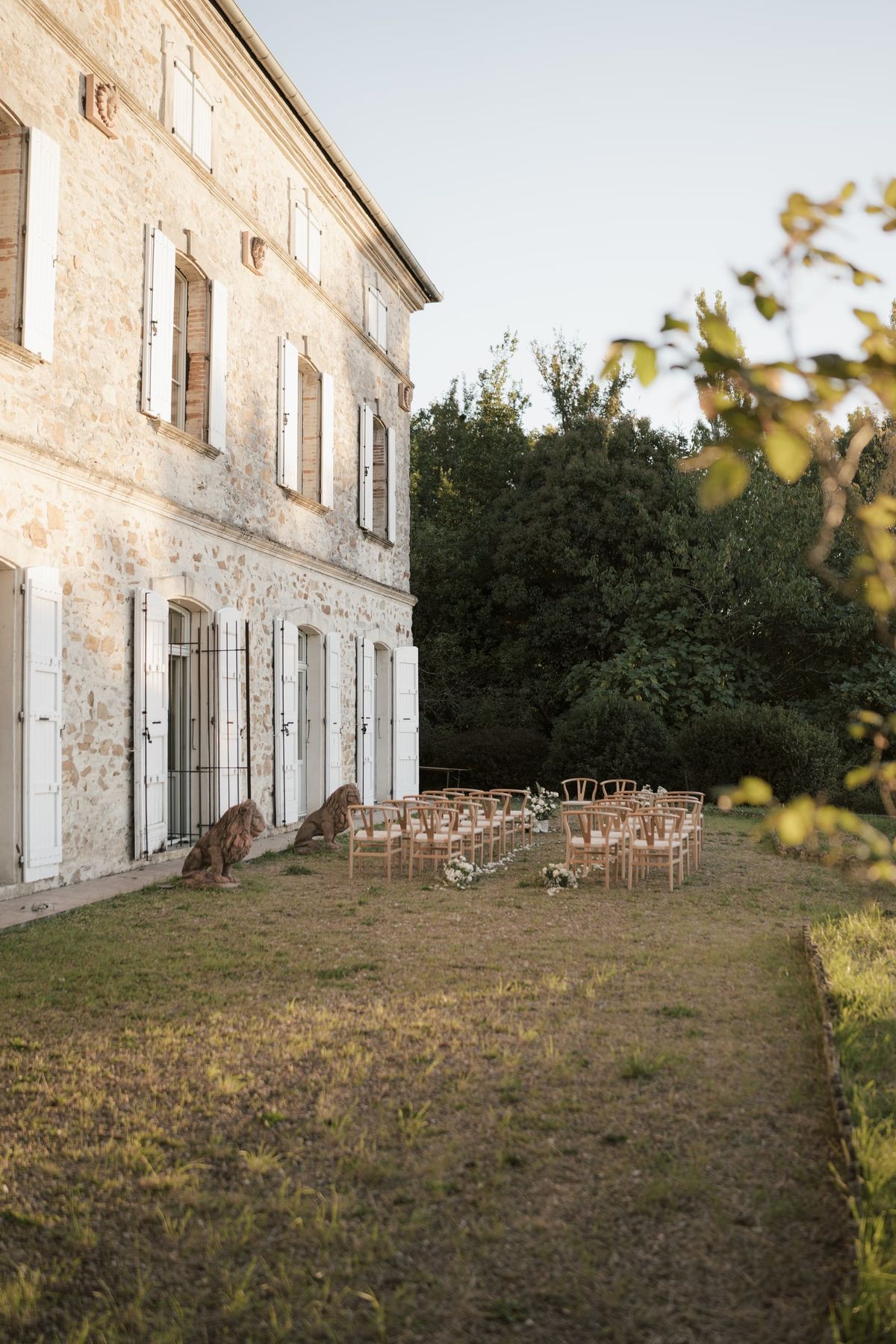 The château's side elevation with shuttered windows, rows of chairs set out on the lawn beyond