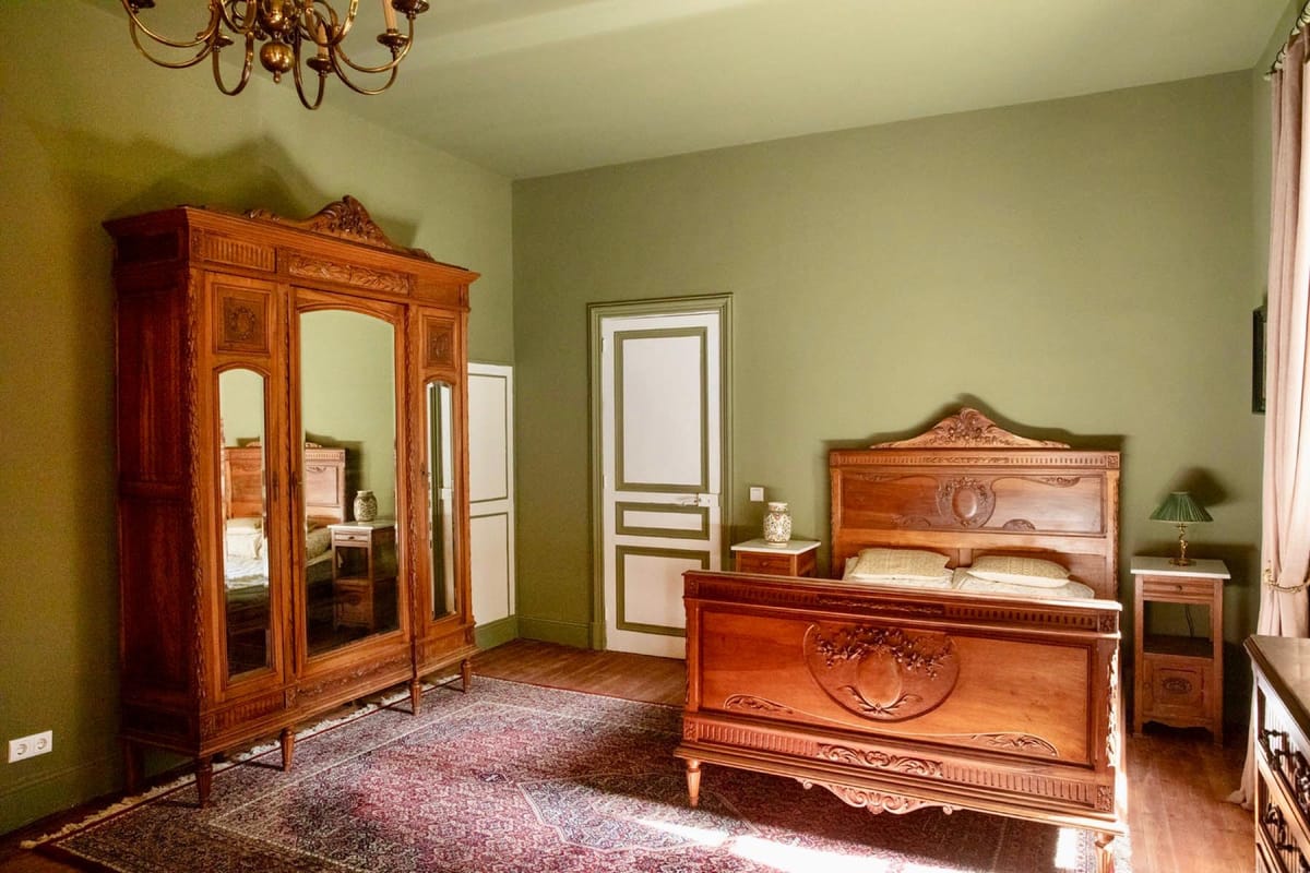 A château bedroom furnished with an antique carved wardrobe and bed.