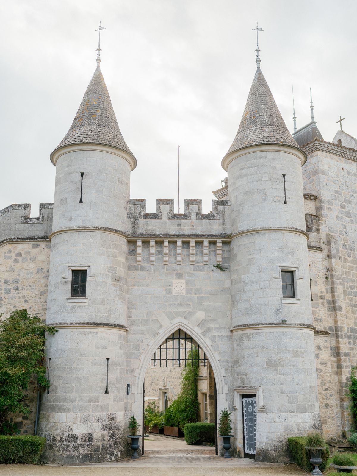 Twin round towers with slate cone roofs and battlements framing the arched gatehouse entrance