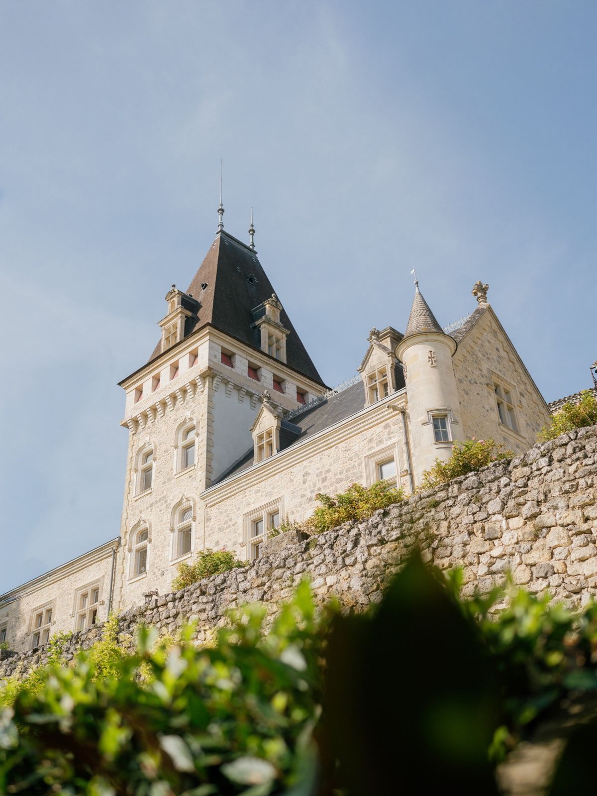 The château's main tower with dormer windows rising above an old stone wall