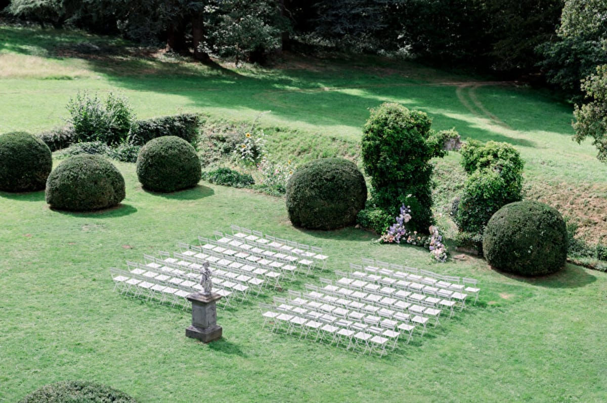 Aerial view of outdoor ceremony seating arranged in a formal garden with topiary at Château de Méridon