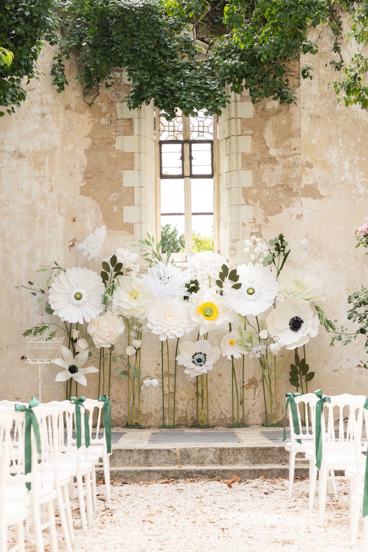 Ceremony seating at Chateau du Pordor set before an oversized white anemone installation against the chapel's stone wall
