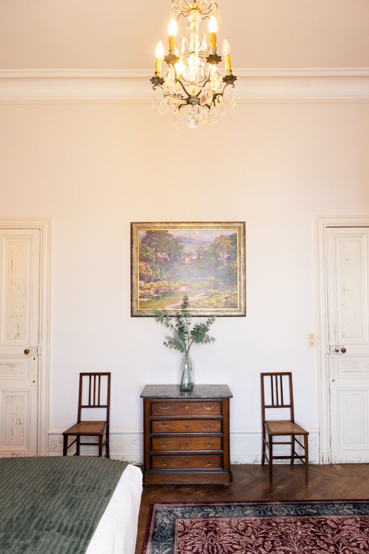 The Duke and Duchess suite at Chateau du Pordor, with a chandelier, antique chest and a framed landscape