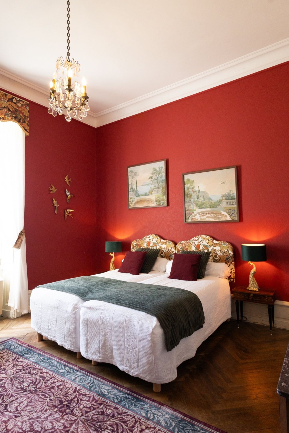 Red-walled bedroom in the Duke and Duchess suite at Chateau du Pordor, with a gilded headboard and herringbone parquet
