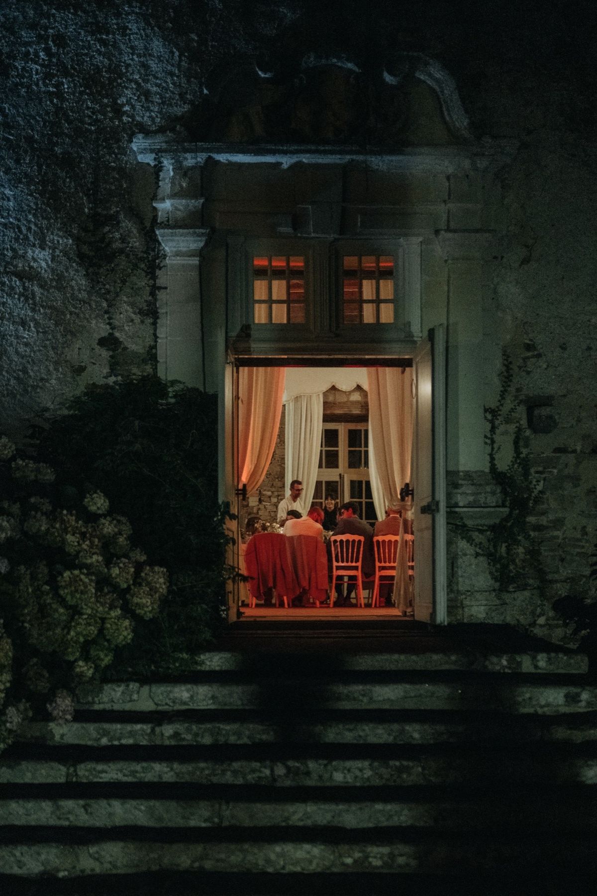 The lit doorway at Chateau du Pordor in the evening, with the wedding dinner visible inside