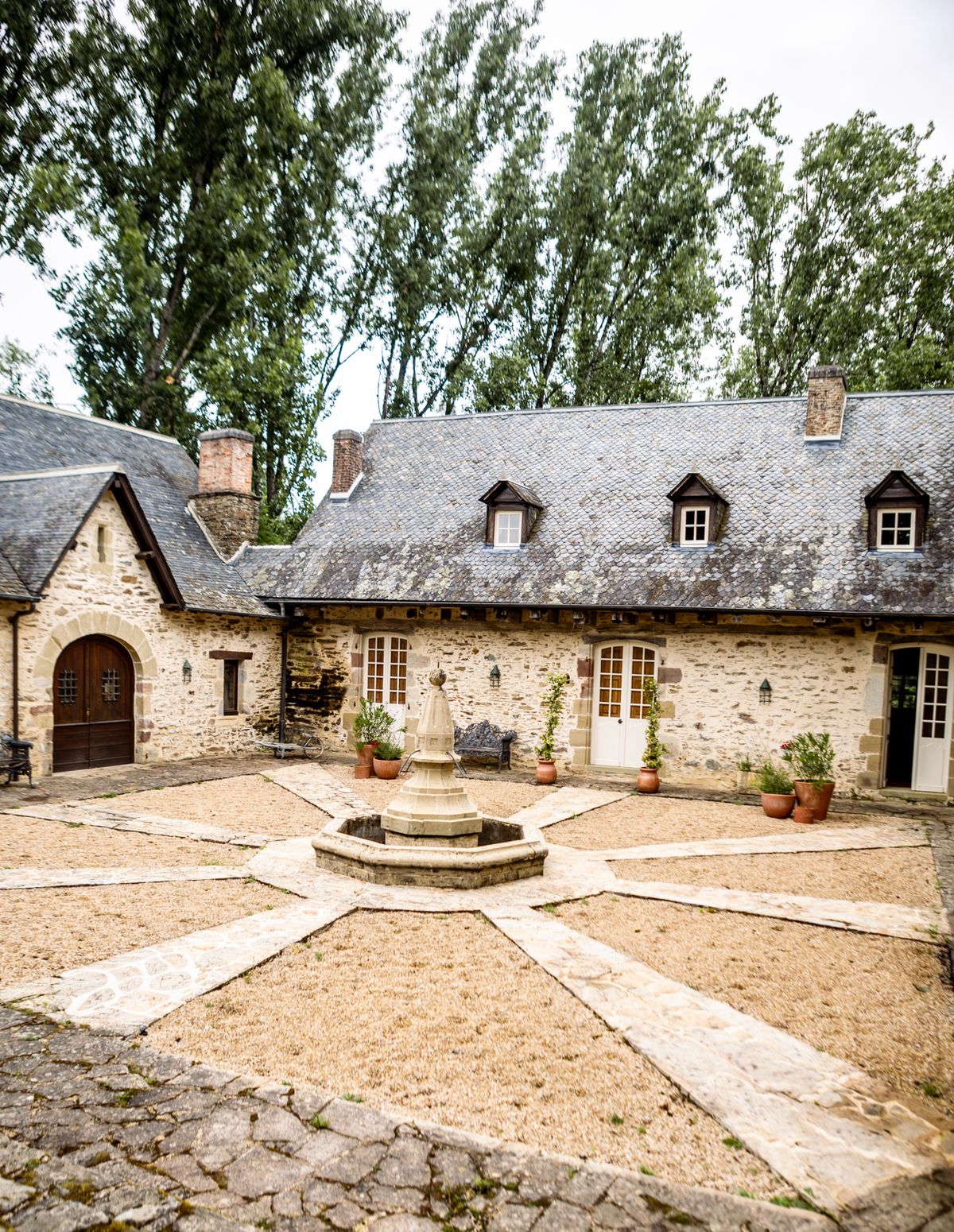 Chateau Eyparsac cobbled courtyard with a central stone fountain framed by arched stone outbuildings