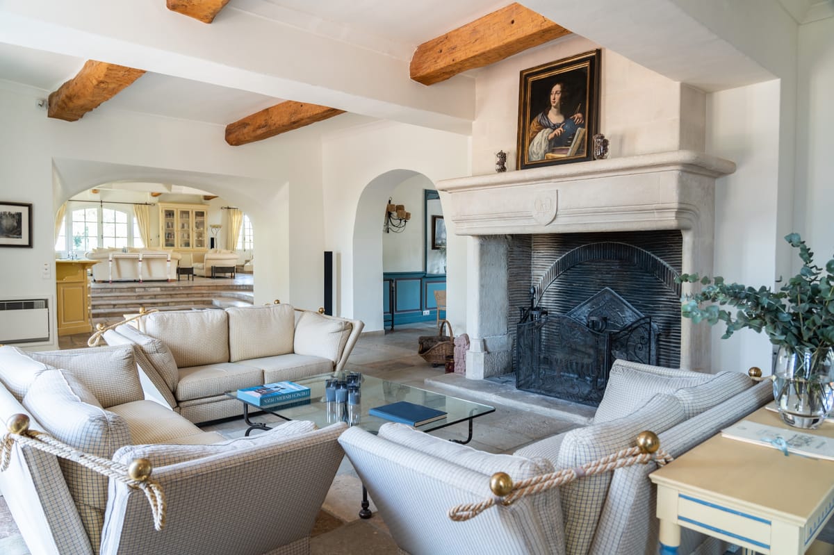 Living room with beamed ceiling and stone fireplace at Chateau les Crostes