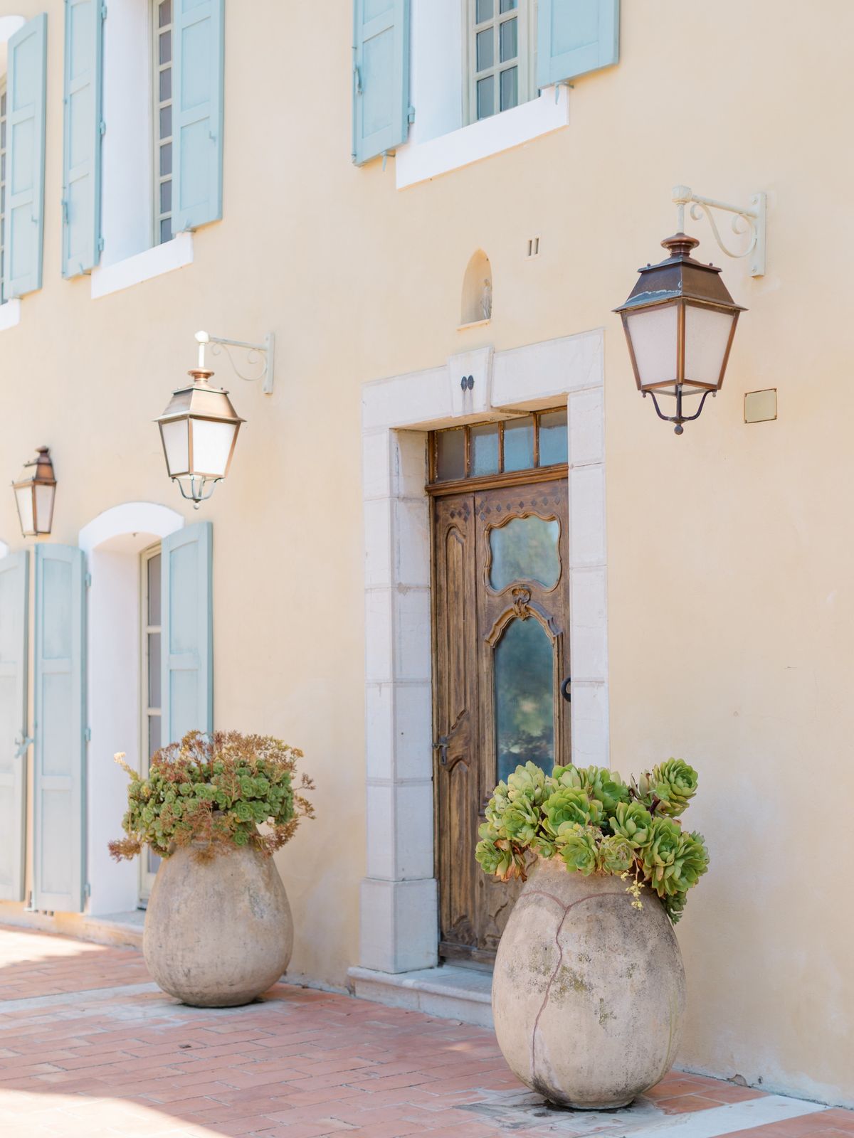 Carved wooden entrance door and olive-jar planters at Chateau les Crostes