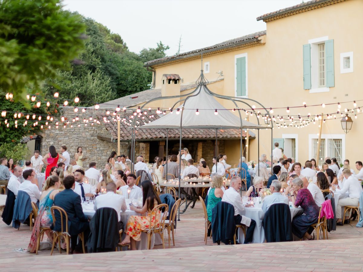 Guests at an outdoor wedding dinner under festoon lights at Chateau les Crostes