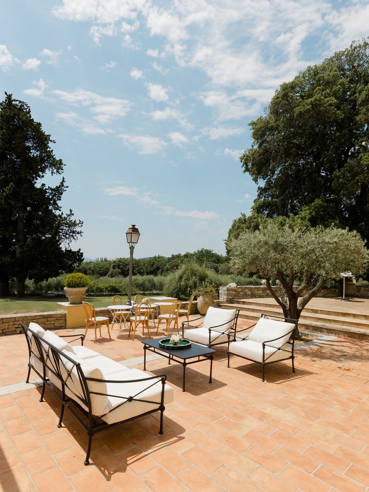 Wrought-iron terrace lounge seating with an olive tree and the countryside beyond