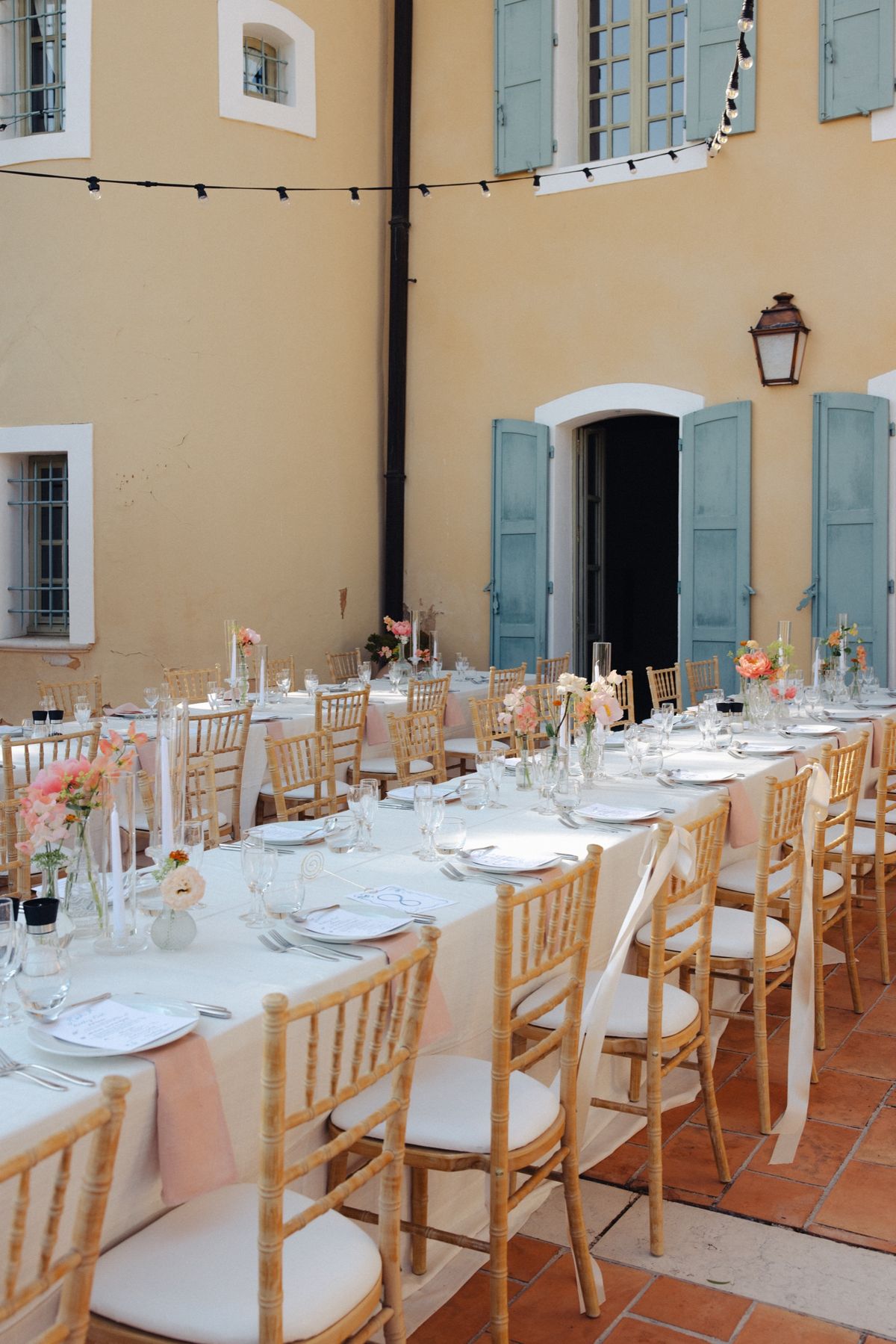 Long wedding tables set with peach flowers in the courtyard at Chateau les Crostes