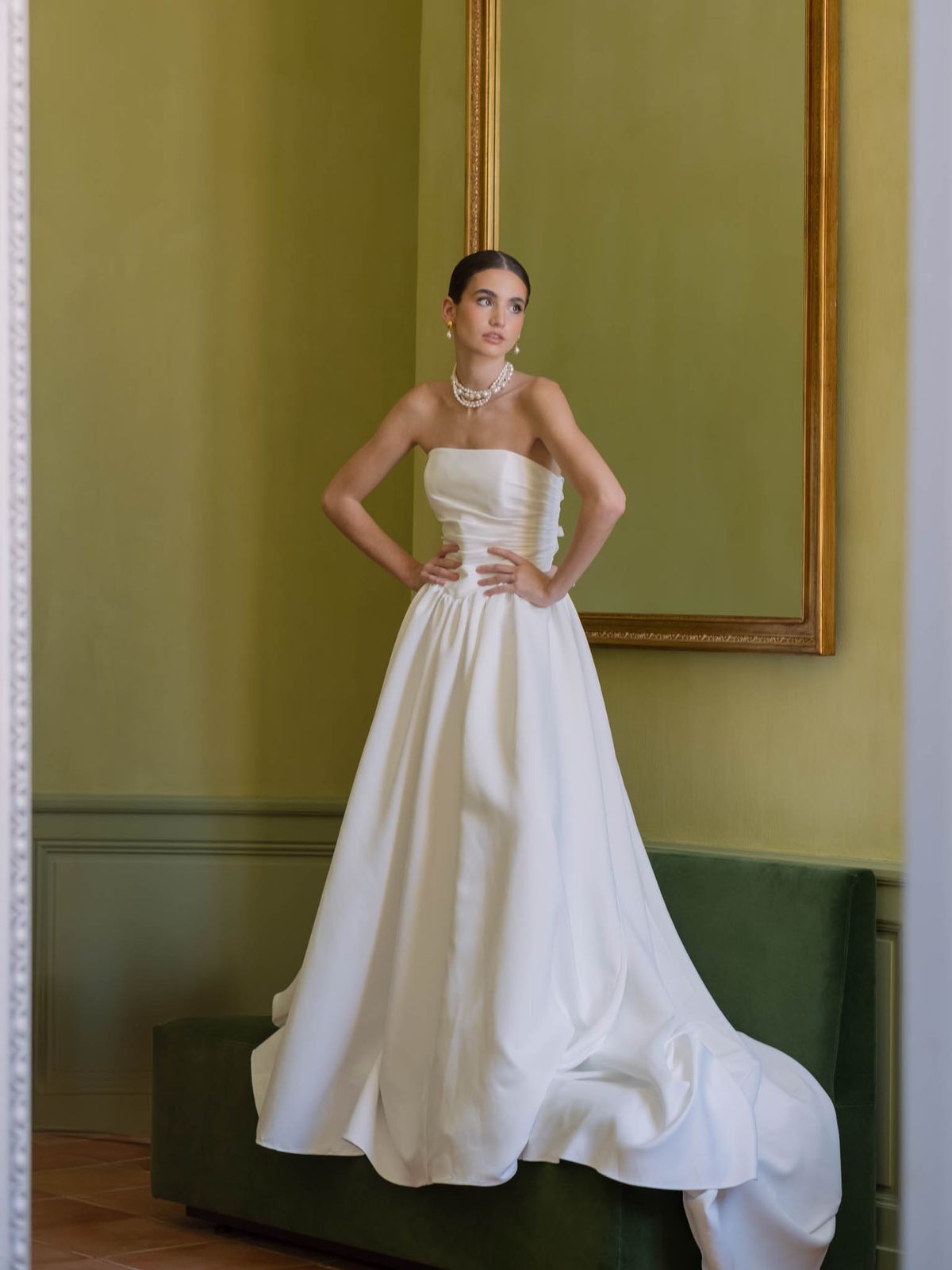 Bride in strapless gown and pearl choker posed in Château de l'Hospital's olive-green reception room