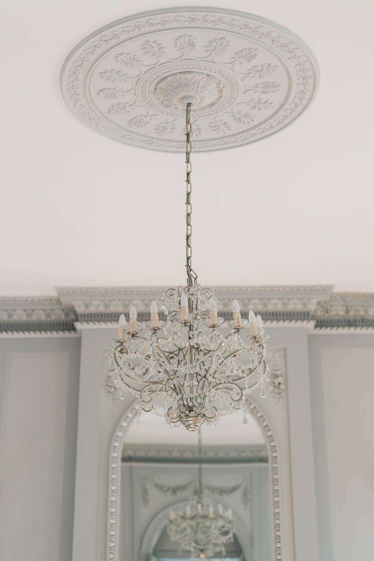 Crystal chandelier beneath an ornate plaster ceiling medallion at Château de l'Hospital