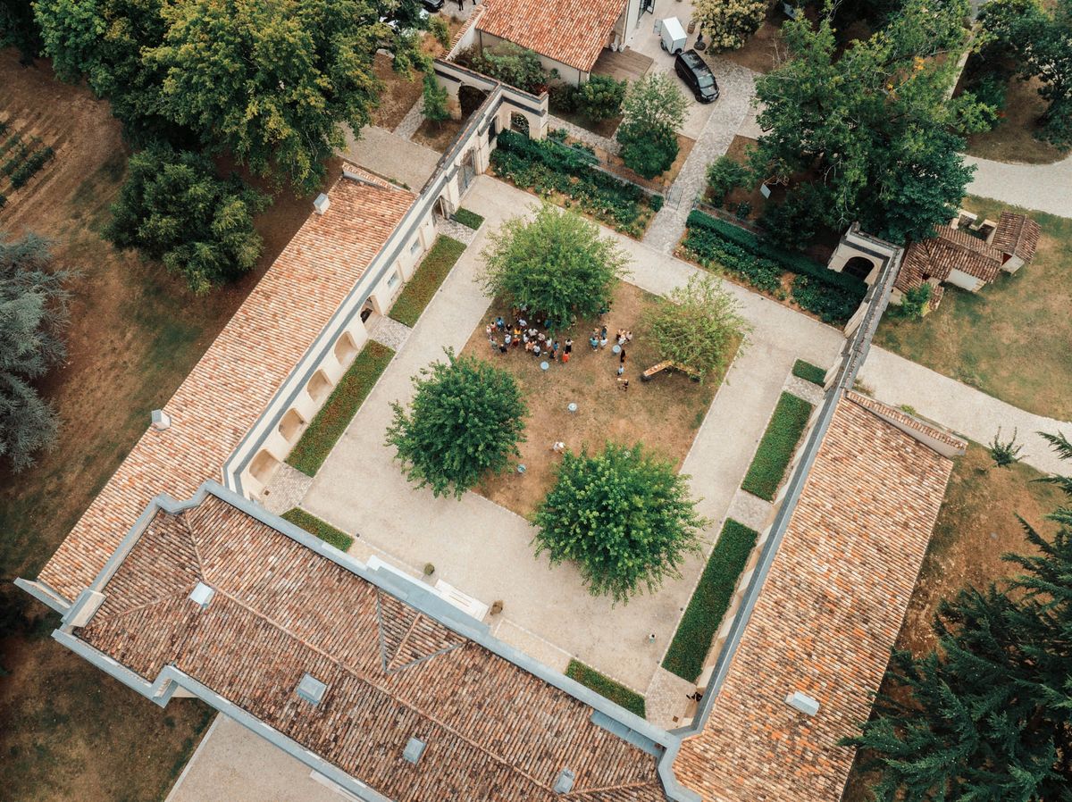 Overhead aerial of Chateau de l'Hospital showing terracotta roof, courtyards and parterre gardens