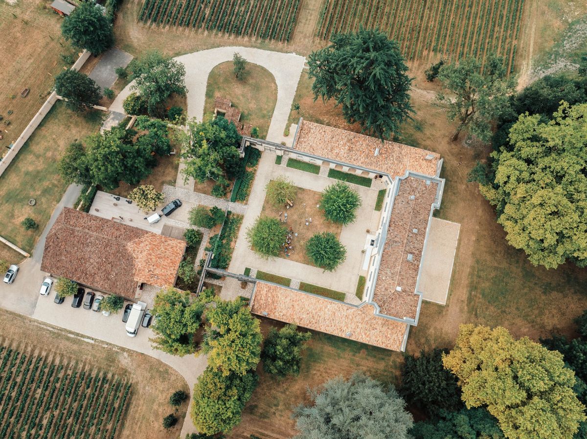 Drone view of Chateau de l'Hospital with organic Graves vineyard rows in the foreground