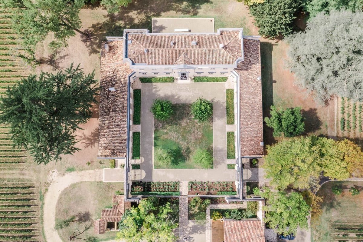 Top-down drone shot of the chateau rooftop with walled parterre garden and outbuildings