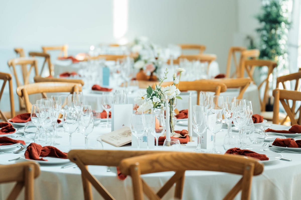 Close-up of a round dining table in the Orangery Hall with terracotta napkins, ivory florals, candles and menu cards