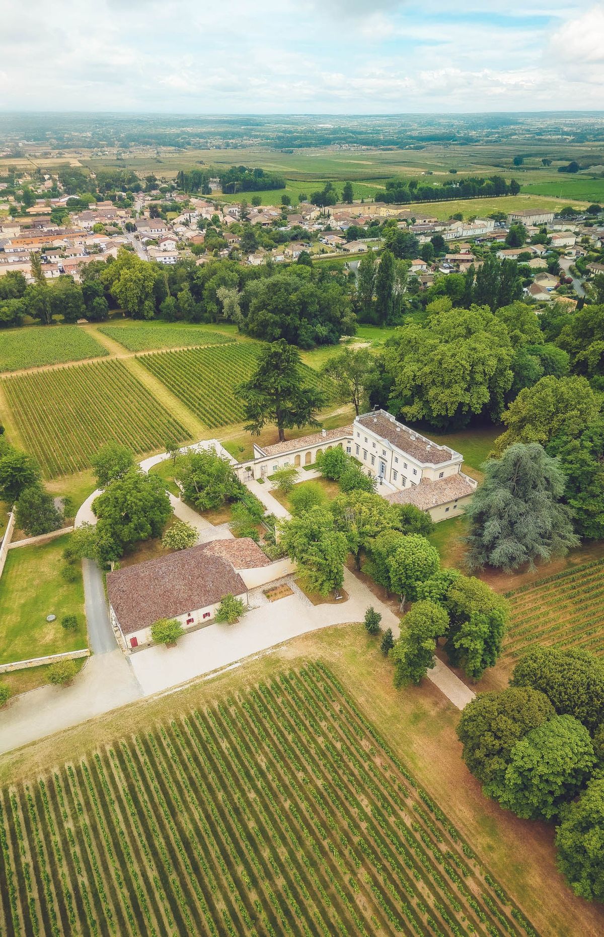 Wide aerial of Chateau de l'Hospital with vineyards, village of Portets and the surrounding Graves countryside