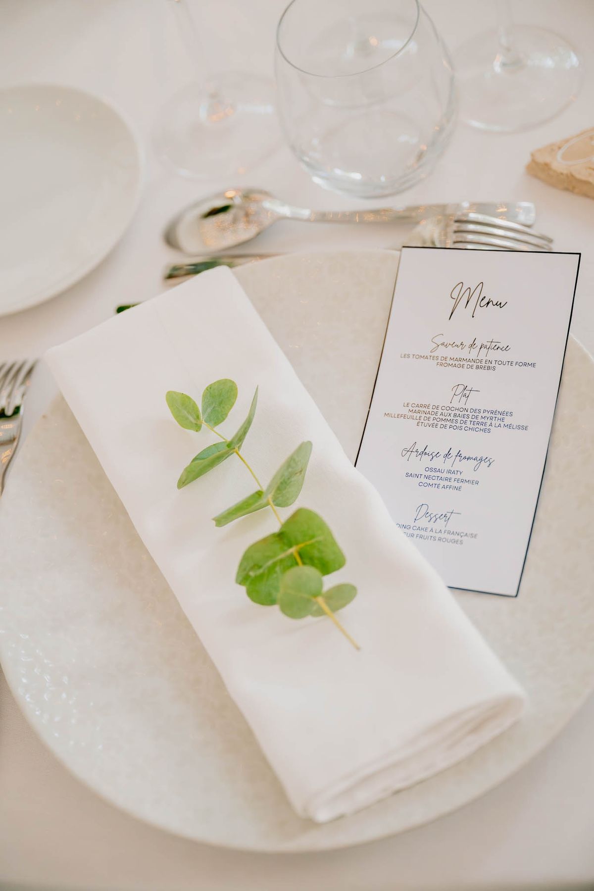 Close-up of a menu card on a folded linen napkin with a sprig of eucalyptus at Chateau de l'Hospital