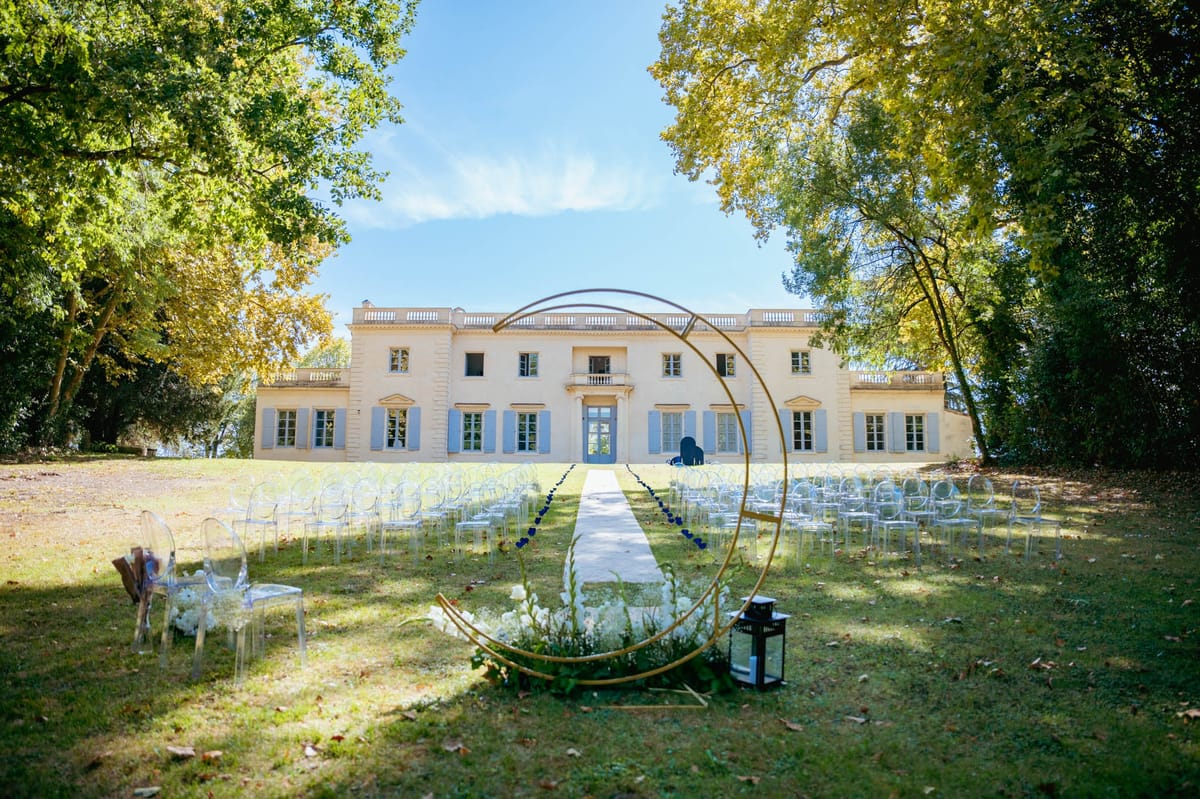 Front facade of Chateau de l'Hospital with a circular floral ceremony arch set at the end of the aisle