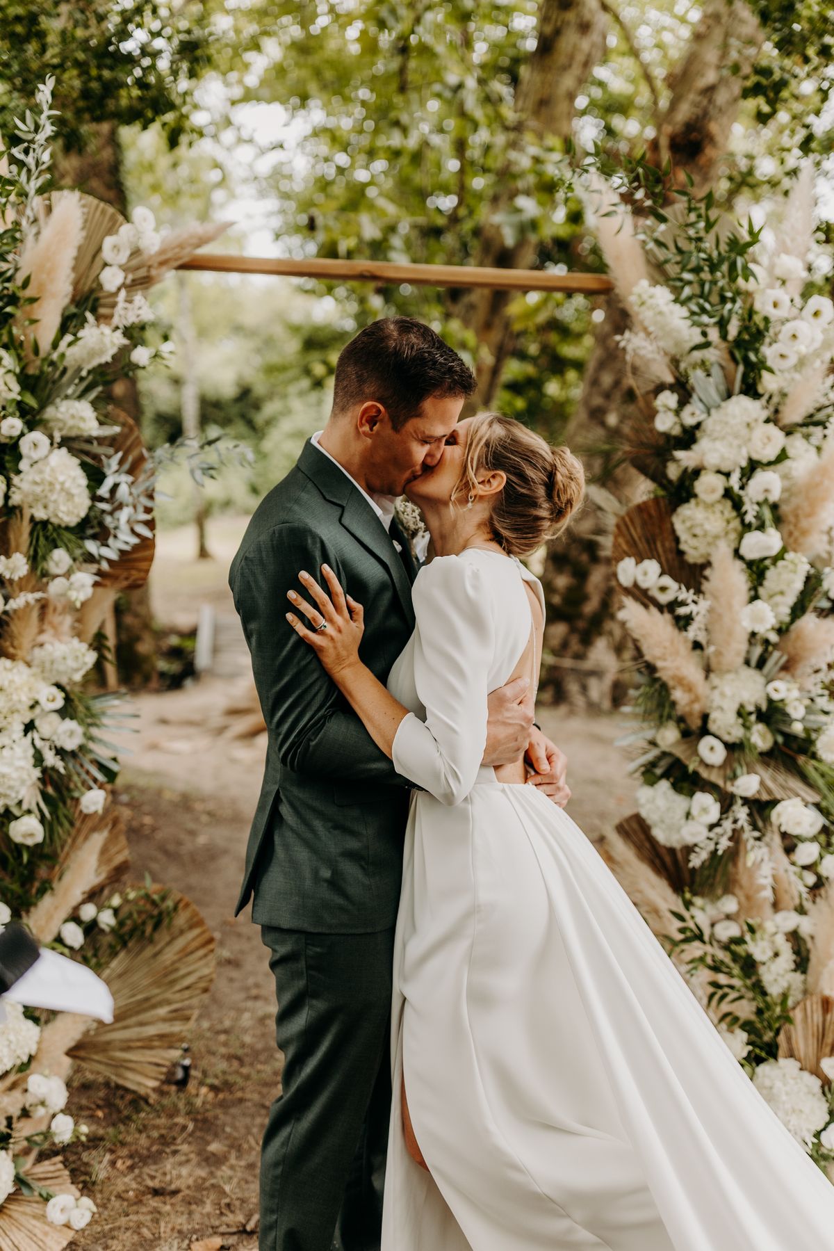 Newlyweds sharing their first kiss under the floral ceremony arch