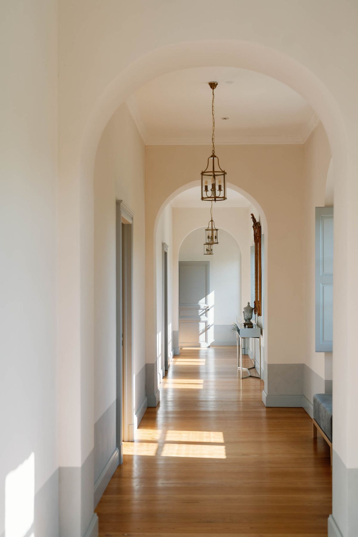 Arched château hallway with brass lantern, upholstered bench and period mirror