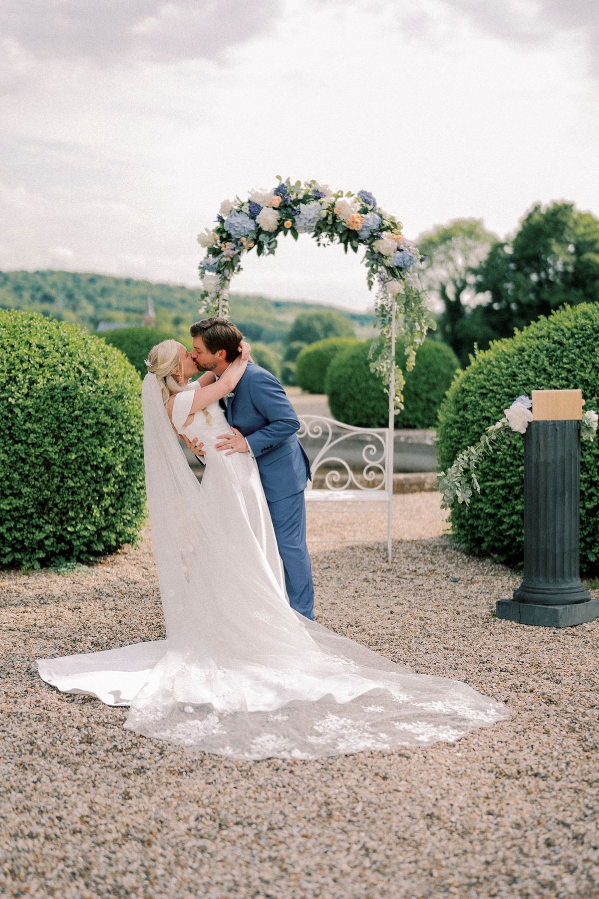 A couple beneath the flowered ceremony arch on the gravel garden terrace