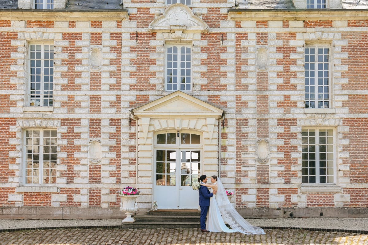 A couple at the central doorway of the château on the cobbled forecourt