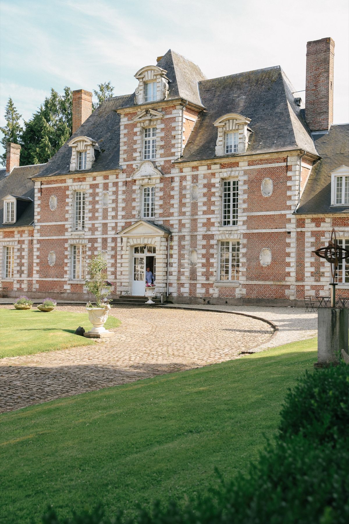 The château entrance with stone urns and the cobbled circular forecourt