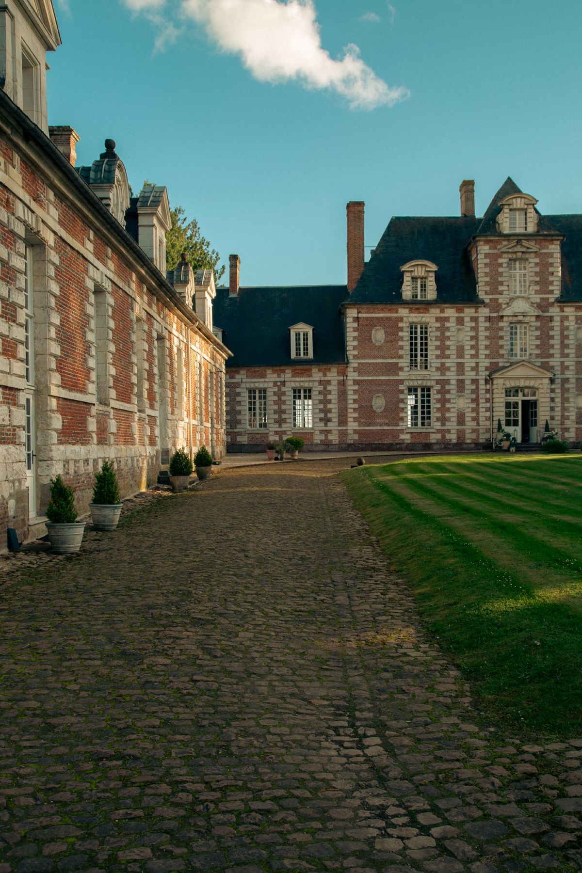 The cobbled drive running alongside the château wing with potted topiary