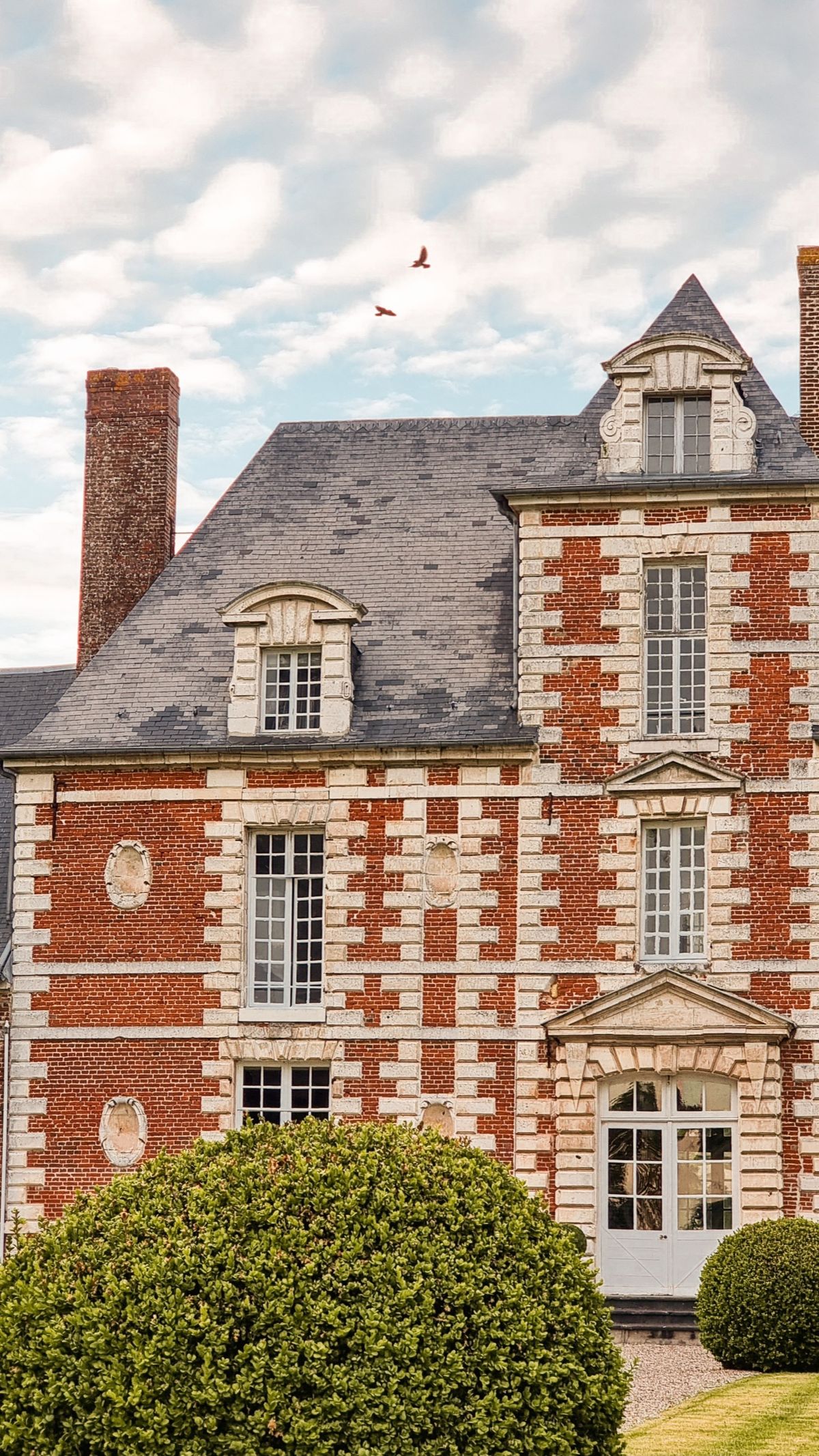 Detail of the château facade showing the chequerboard brick and stone and the slate mansard roof