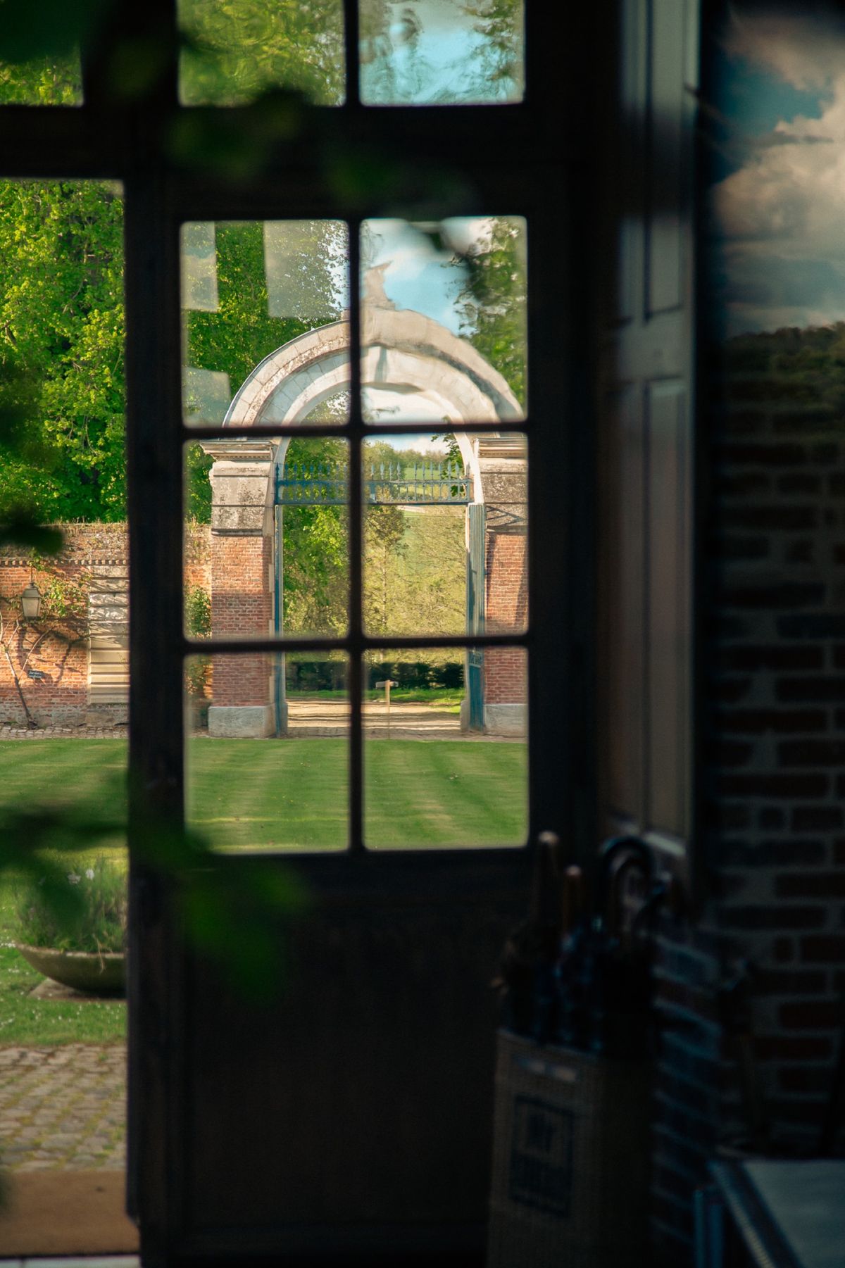 Looking out through a glazed garden door to the lawn and the stone arch beyond