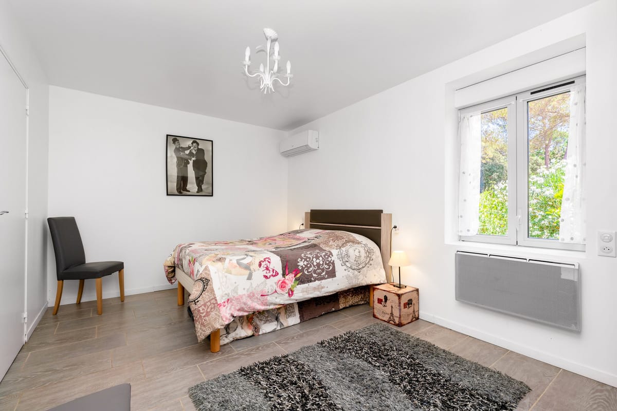 The accessible ground-floor bedroom in the Les Vignes gite, with a double bed, a wall-mounted air conditioning unit and a window onto the garden.