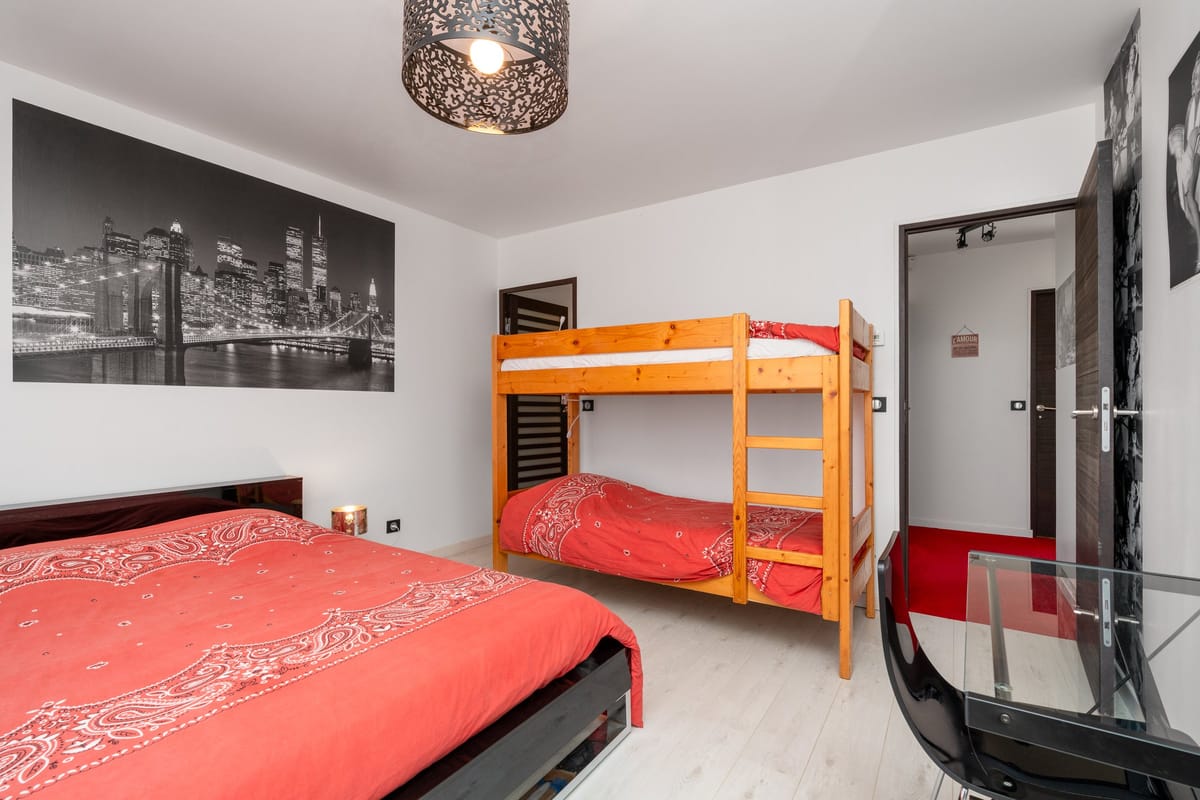 A bedroom in one of the private villas, with a double bed, a pine bunk bed and a glass balustrade onto the stairs.