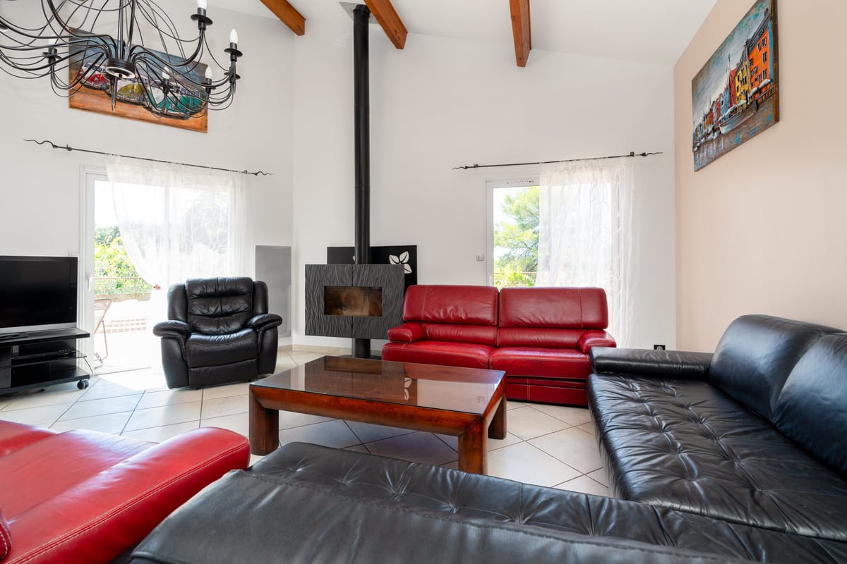 A living room in one of the private villas, with a wood-burning stove, red and black leather sofas and doors onto the garden.