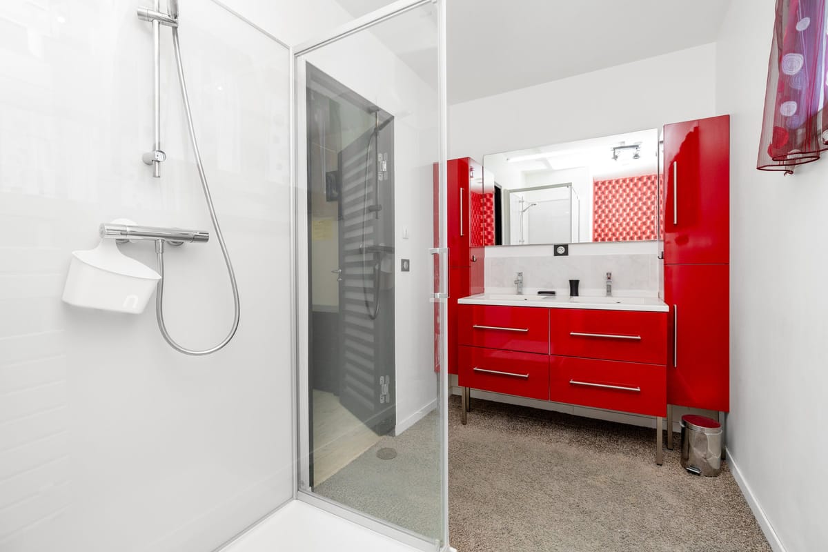 A shower room in one of the private villas, with a walk-in shower and a red gloss vanity with twin basins.